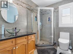 Wood-finish vanity with a dark countertop and glass vessel sink - 