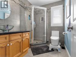 Glass-enclosed shower with pebble-tile floor, wood-finish vanity with vessel sink, wall-mounted mirror, and tile flooring - 