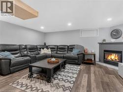 Built-in fireplace with mantel, recessed ceiling lighting, wood-finish flooring, and a window with horizontal blinds - 