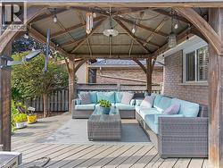 Expansive outdoor deck featuring a wooden gazebo with a metal roof, string lighting, and exterior brick siding - 