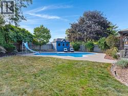 Expansive backyard featuring a freeform swimming pool, concrete pool surround, and a blue shed with white trim - 