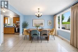 Expansive window, overhead chandelier, light-colored flooring, kitchen with wood cabinetry - 