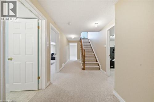 Carpeted staircase with wood banister and handrail, recessed lighting, white six-panel interior doors, and neutral wall tones - 61 Sunnyside Drive, St. George, ON 