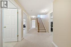 Carpeted staircase with wood banister and handrail, recessed lighting, white six-panel interior doors, and neutral wall tones - 