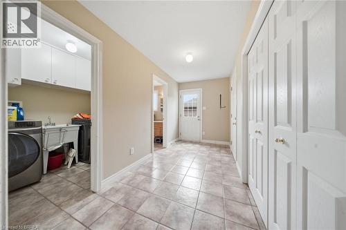 Tile flooring throughout, white bi-fold closet doors, laundry room with built-in cabinetry, utility sink, and washer/dryer hookups, and exterior door with window panes - 61 Sunnyside Drive, St. George, ON 