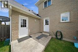 Brick exterior with two white exterior doors, concrete patio, and a shingled roof - 