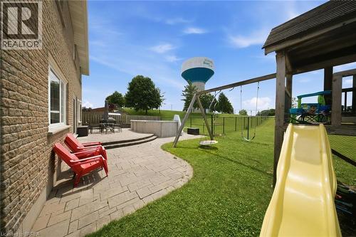 Brick exterior with white window trim, paver patio, and grassy yard with a wooden playset - 61 Sunnyside Drive, St. George, ON 