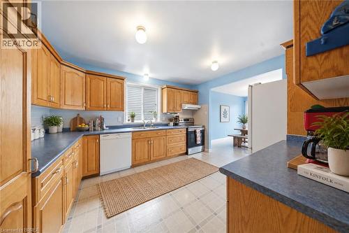 Kitchen with wood cabinetry, blue countertops, tile flooring, and integrated white appliances - 61 Sunnyside Drive, St. George, ON 
