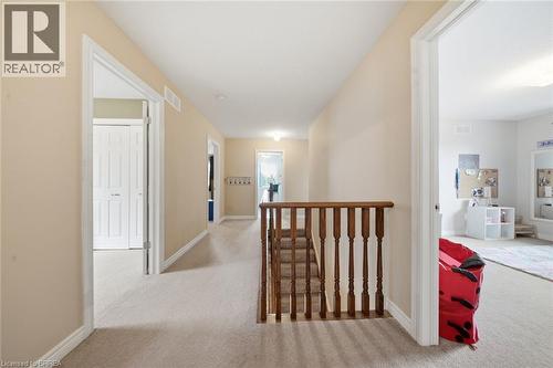 Carpeted hallway with painted walls, white trim, and wood balusters - 61 Sunnyside Drive, St. George, ON 