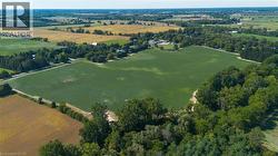 Expansive agricultural land featuring a large cultivated field and surrounding mature trees - 
