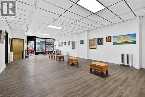 Spacious interior featuring wood-finish flooring, drop ceiling with recessed lighting, track lighting, and a large front window - 689 Barton Street E, Hamilton, ON 