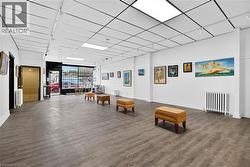 Spacious interior featuring wood-finish flooring, drop ceiling with recessed lighting, track lighting, and a large front window - 