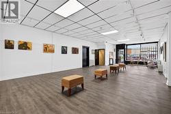 Wide-plank wood-finish flooring, drop ceiling with integrated lighting, track lighting, and a prominent front window - 