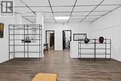 Wood-finish flooring, white walls, and a drop ceiling with integrated lighting - 