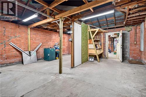 Exposed brick walls, concrete flooring, exposed wood beam ceiling, fluorescent overhead lighting, and an internal doorway - 689 Barton Street E, Hamilton, ON 