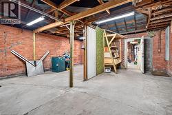 Exposed brick walls, concrete flooring, exposed wood beam ceiling, fluorescent overhead lighting, and an internal doorway - 
