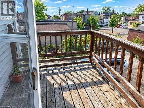 Outdoor wooden deck featuring a wooden railing and a white screen door - 689 Barton Street E, Hamilton, ON 