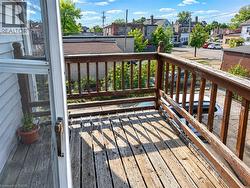 Outdoor wooden deck featuring a wooden railing and a white screen door - 