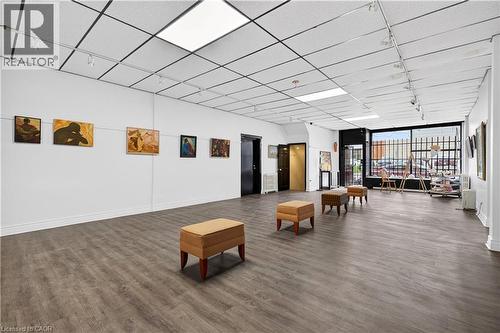 Wide-plank wood-finish flooring, drop ceiling with integrated lighting, track lighting, and a prominent front window - 689 E Barton Street E, Hamilton, ON 