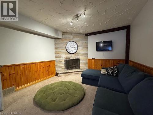 Stone fireplace with hearth, wood-paneled walls, track lighting, and carpeted flooring - 511 Havelock Drive, Waterloo, ON 