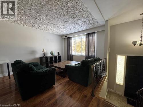 Wood-finish flooring, textured ceiling, and large window with dark drapery - 511 Havelock Drive, Waterloo, ON 