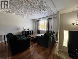 Wood-finish flooring, textured ceiling, and large window with dark drapery - 
