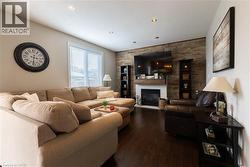 Wood-finish flooring throughout, featuring a stone accent wall, recessed lighting, and a built-in fireplace with a mantel - 
