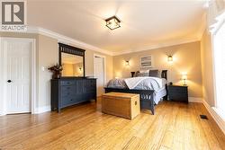 Wood-finish flooring, crown molding, white trim, recessed wall sconces, and a multi-pane window - 