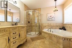 Dual vanity with ornate cabinetry, glass-enclosed shower, built-in soaking tub, and coordinated tile flooring - 
