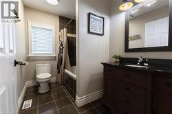 Wood-finish vanity with a dark countertop, white undermount sink, and chrome faucet - 