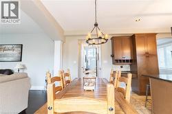Open-concept dining area featuring a dark wood finish table, overhead chandelier, and recessed lighting - 