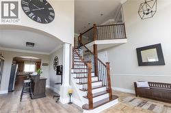 Staircase with wood treads and wrought iron spindles, high ceilings, arched entryway, upper landing, and wood-finish flooring - 