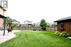 Expansive lawn with a wooden privacy fence, a detached wooden shed, and a curved concrete patio - 