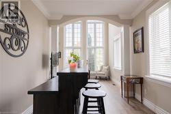 Arch-top window with transoms, wood-finish flooring, crown molding, and a built-in bar - 