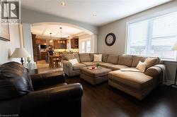Recessed lighting illuminates the living area with dark wood-finish flooring - 