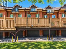 Brick exterior featuring multiple private balconies with black railings, individual garage doors, and elevated wood privacy fencing - 
