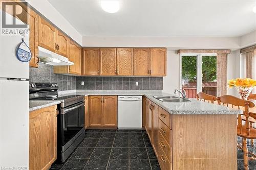 Kitchen featuring wood-finish cabinetry, black tile flooring, and a sliding glass door - 5180 Oakley Drive, Burlington, ON 