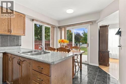 Kitchen area featuring wood cabinetry, a double basin sink, and stone-look countertops - 5180 Oakley Drive, Burlington, ON 