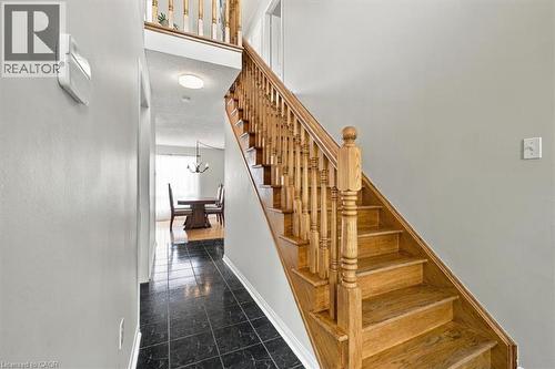 Wood staircase with balusters, black tile flooring, and light gray wall paint - 5180 Oakley Drive, Burlington, ON 