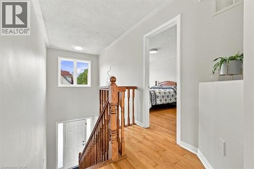 Bright upper-level hallway showcasing warm wood-finish flooring, crisp white walls, and abundant natural light from a multi-pane window - 5180 Oakley Drive, Burlington, ON 