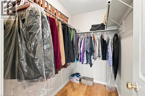 Dedicated closet space featuring dual hanging rods with multiple tiers for organized storage, wood-finish flooring, and white painted walls with ample natural light from recessed ceiling fixtures - 5180 Oakley Drive, Burlington, ON 