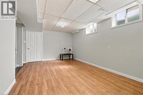 Light wood-finish flooring, light gray walls, drop ceiling, and white trim - 5180 Oakley Drive, Burlington, ON 