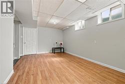 Light wood-finish flooring, light gray walls, drop ceiling, and white trim - 