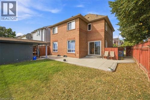 Brick exterior with multiple windows, sliding glass door, concrete patio, and fenced yard - 5180 Oakley Drive, Burlington, ON 
