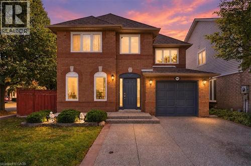 Brick facade with white window frames, an arched front entry, an attached garage, and a concrete driveway - 5180 Oakley Drive, Burlington, ON 