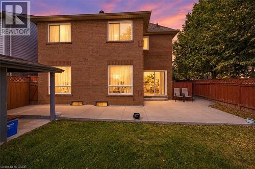 Brick exterior with multiple windows, a concrete patio, and a sliding glass door - 5180 Oakley Drive, Burlington, ON 