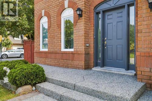 Brick facade featuring arched window details, a paneled entry door with sidelights, and exterior lighting fixtures - 5180 Oakley Drive, Burlington, ON 