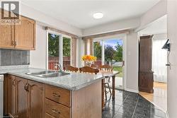 Kitchen area featuring wood cabinetry, a double basin sink, and stone-look countertops - 