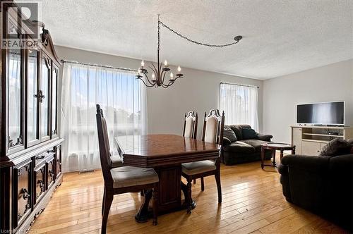 Wood-finish flooring throughout, featuring a chandelier above the dining area and large windows - 5180 Oakley Drive, Burlington, ON 