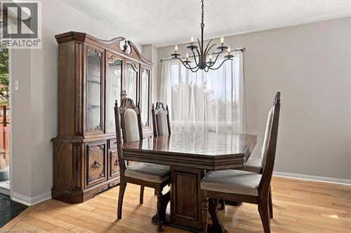 Elegant dining room showcasing hardwood flooring, a dark wood pedestal dining table with seating for four, and upholstered chairs with tall backs - 5180 Oakley Drive, Burlington, ON 